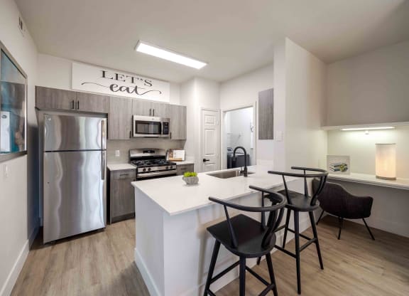 a kitchen with stainless steel appliances and a counter with chairs