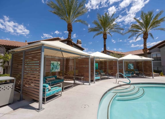 A pool area with a wooden fence and palm trees.