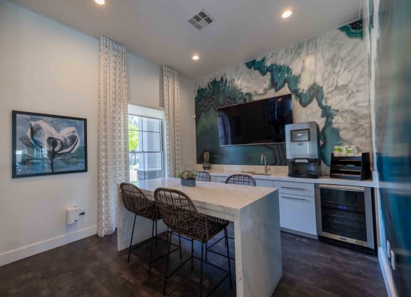 a kitchen with a counter and chairs and a tv