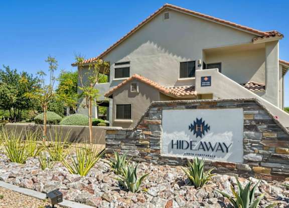 A house with a sign that says HIDEAWAY in front of it.