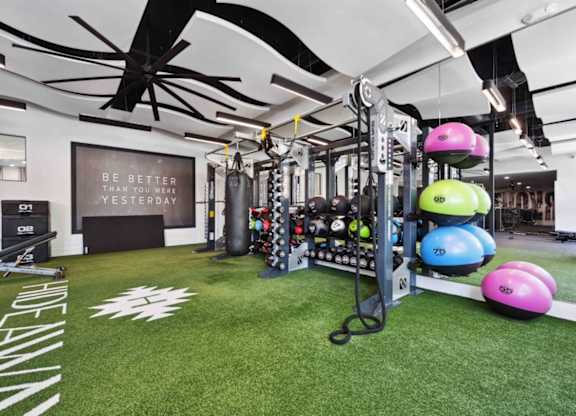 A gym with a green floor and a sign that says "Be better than you were yesterday".