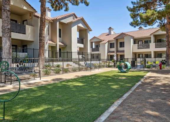 A sunny day at a residential complex with a playground and green lawn.