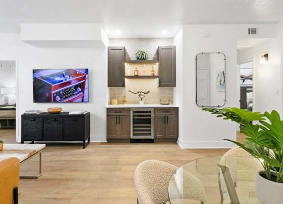 A living room with a television, a cabinet, and a potted plant.