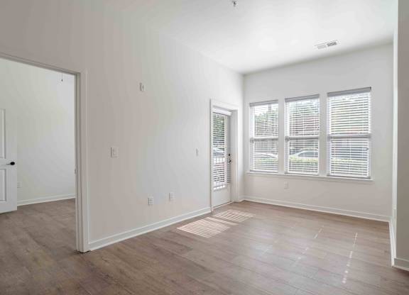 an empty living room with white walls and wood floors