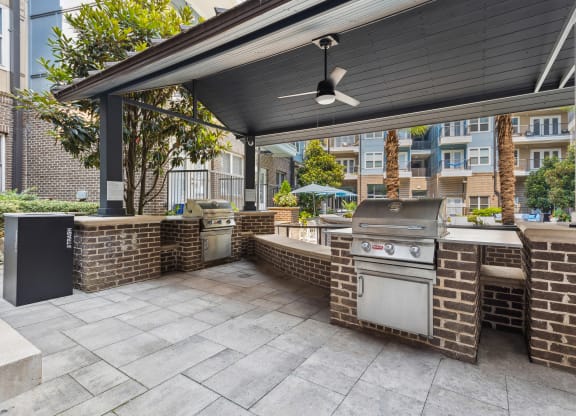 an outdoor kitchen with a grill and a ceiling fan