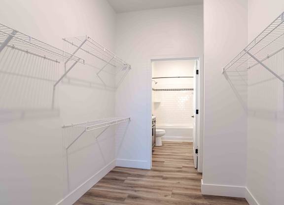an oversized closet with white walls and wood floors