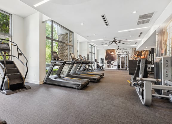 a room filled with cardio equipment and large windows