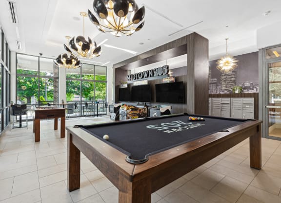a games room with a pool table and two televisions