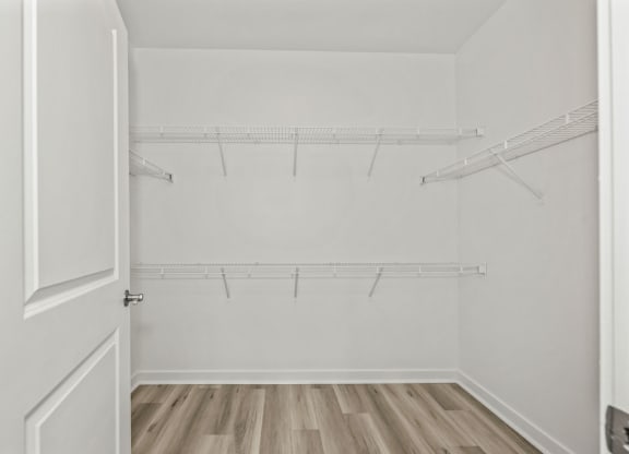 the closet in a bedroom with white walls and wood floors