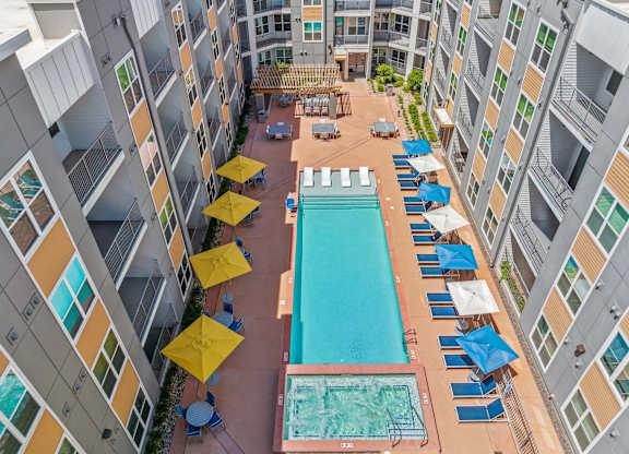 A large swimming pool surrounded by blue lounge chairs and yellow umbrellas.