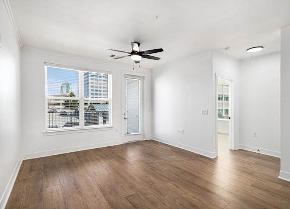 A room with a ceiling fan and a window overlooking a cityscape.