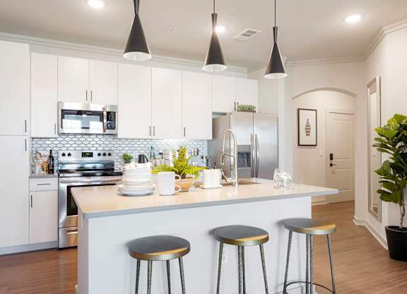 A kitchen with a white counter and bar stools.