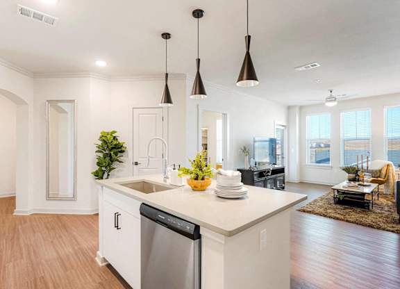 A modern kitchen with a large island and pendant lights.
