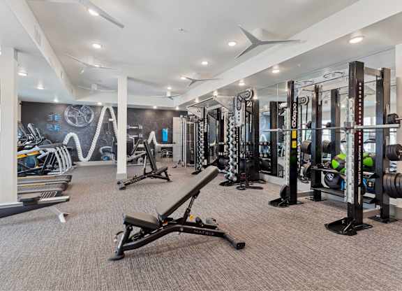 A gym with a variety of equipment including treadmills, weights, and exercise machines.