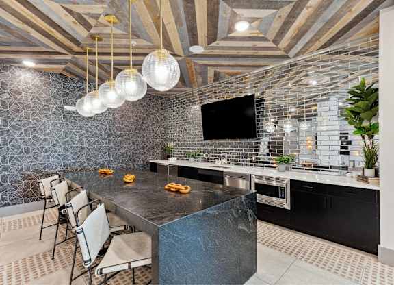 A modern kitchen with a black countertop and a TV mounted on the wall.