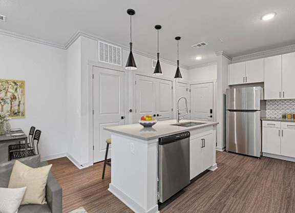 A kitchen with white cabinets and a wooden floor.
