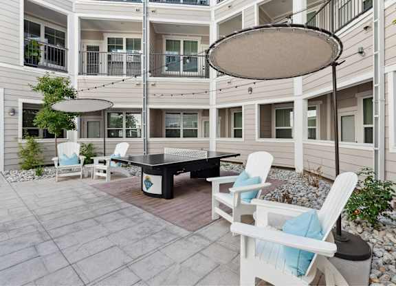 A patio with a table and chairs and a white umbrella.
