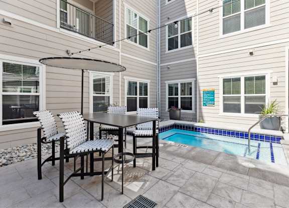 A patio with a table and chairs and a pool.