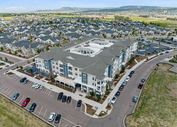 A large apartment complex with a parking lot in front.
