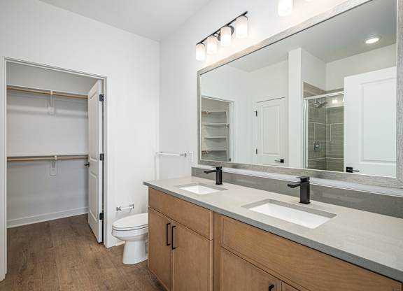 A bathroom with a toilet, sink, and mirror.
