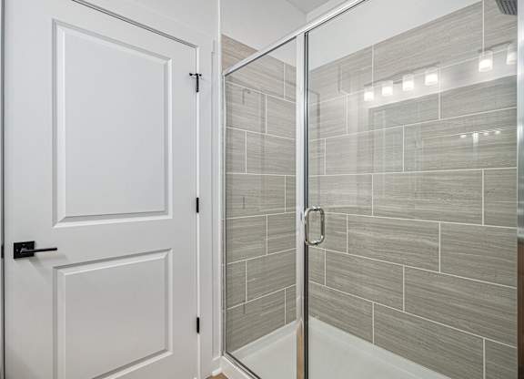 A white door is open to a tiled shower.