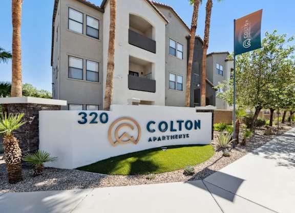 Colton Apartments building with a flag and palm trees in front.