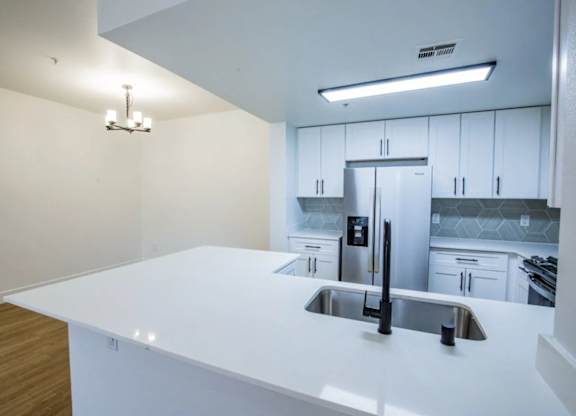 A modern kitchen with a white countertop and stainless steel appliances.