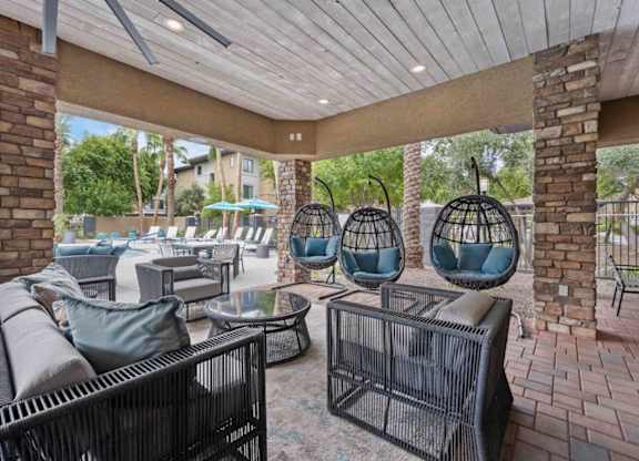 A patio with a black wicker sofa and chairs.