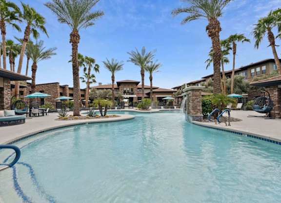 A swimming pool surrounded by palm trees and lounge chairs.
