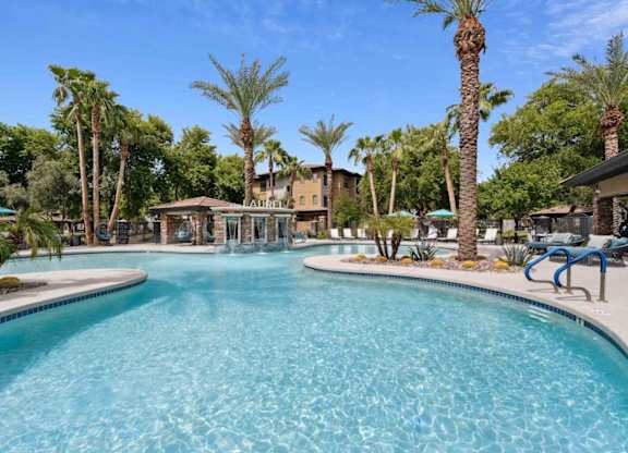 A large swimming pool surrounded by palm trees and lounge chairs.