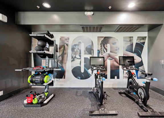 A room with exercise bikes and a wall with a large letter "A" on it.