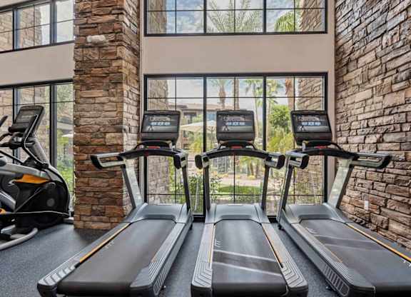 A gym with treadmills and a brick wall.