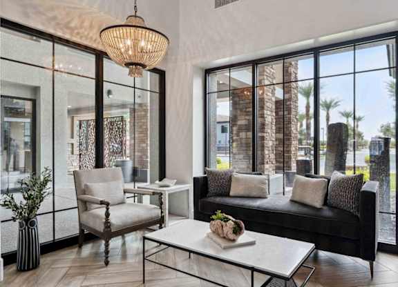 A modern living room with a black couch, a white coffee table, and a large window.