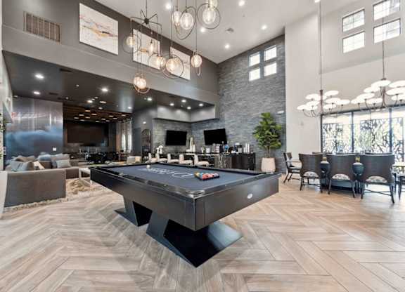 A pool table is in the middle of a room with a stone wall and a bar area.