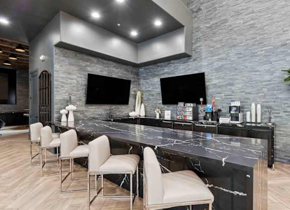 A modern kitchen with a marble countertop and bar stools.