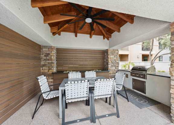 A patio with a table and chairs and a grill.