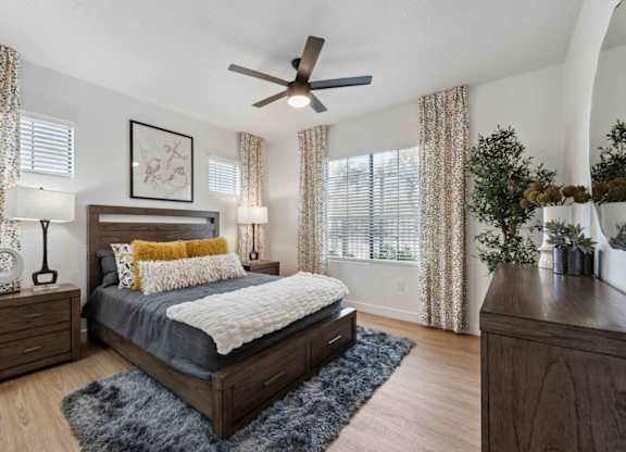 A bedroom with a bed, nightstands, and a ceiling fan.