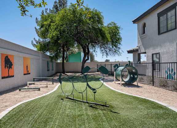 A playground with a swing set and a tree in the middle of a grassy area.