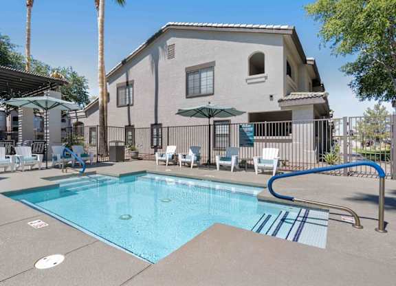 A swimming pool in front of a house with a blue tiled edge.