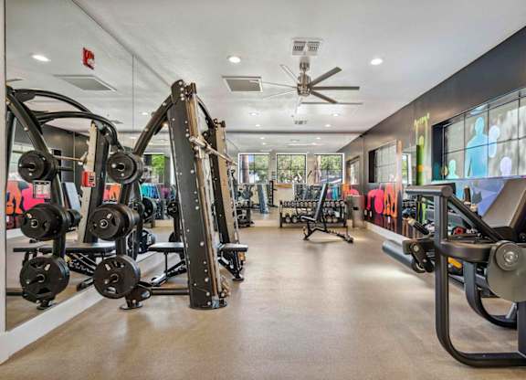 A gym with a variety of equipment including dumbbells, weight machines, and a bench press.