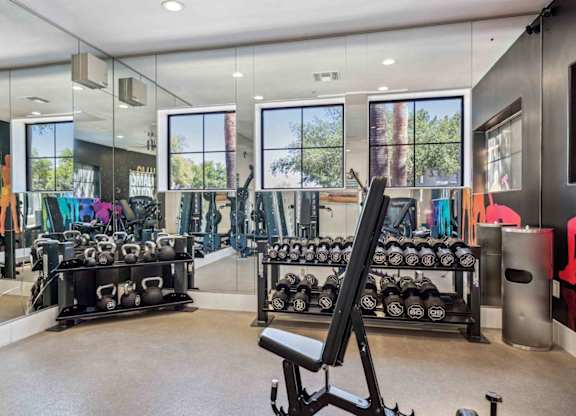 A gym with a variety of equipment including dumbbells and weight machines.