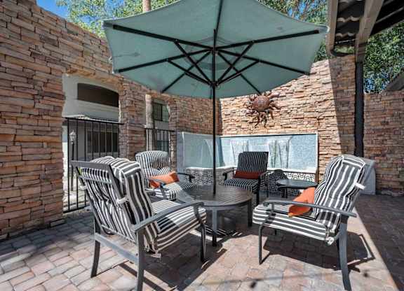 A patio with a table and chairs under an umbrella.