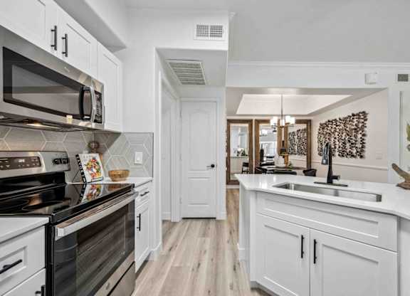 A kitchen with white cabinets and a black stove top oven.