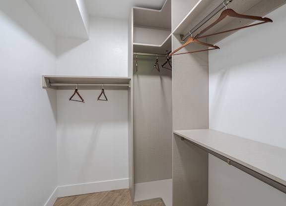 A white closet with a shelf and three hangers.