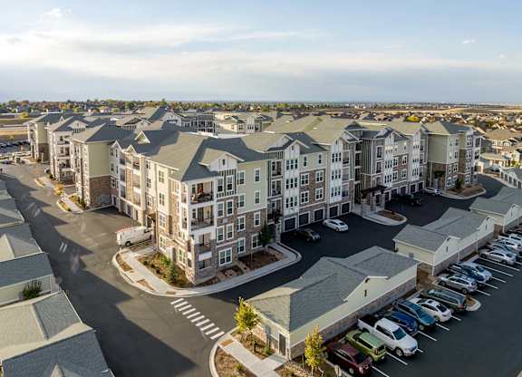 A large apartment complex with a parking lot in front.