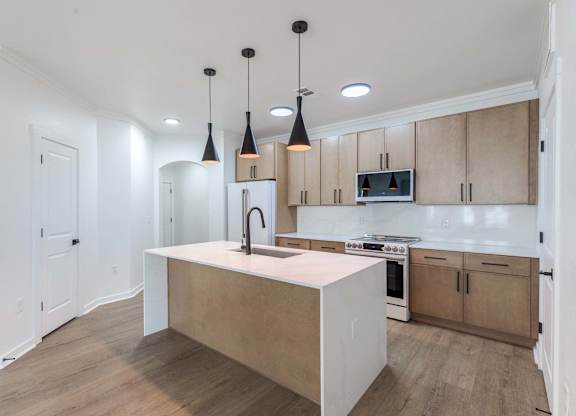 A kitchen with a white island and wooden cabinets.