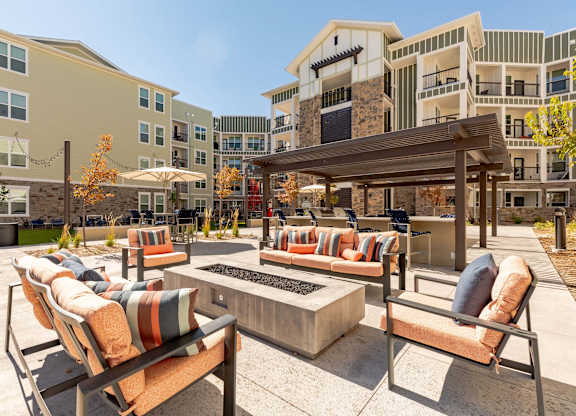 A patio with a fire pit and chairs.