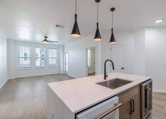 A kitchen with a sink, stove, and a ceiling fan.