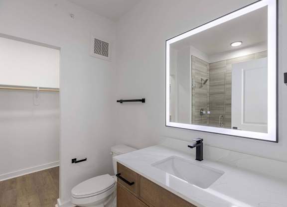 A white bathroom with a toilet, sink and mirror.