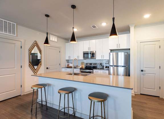 A kitchen with a white counter and bar stools.